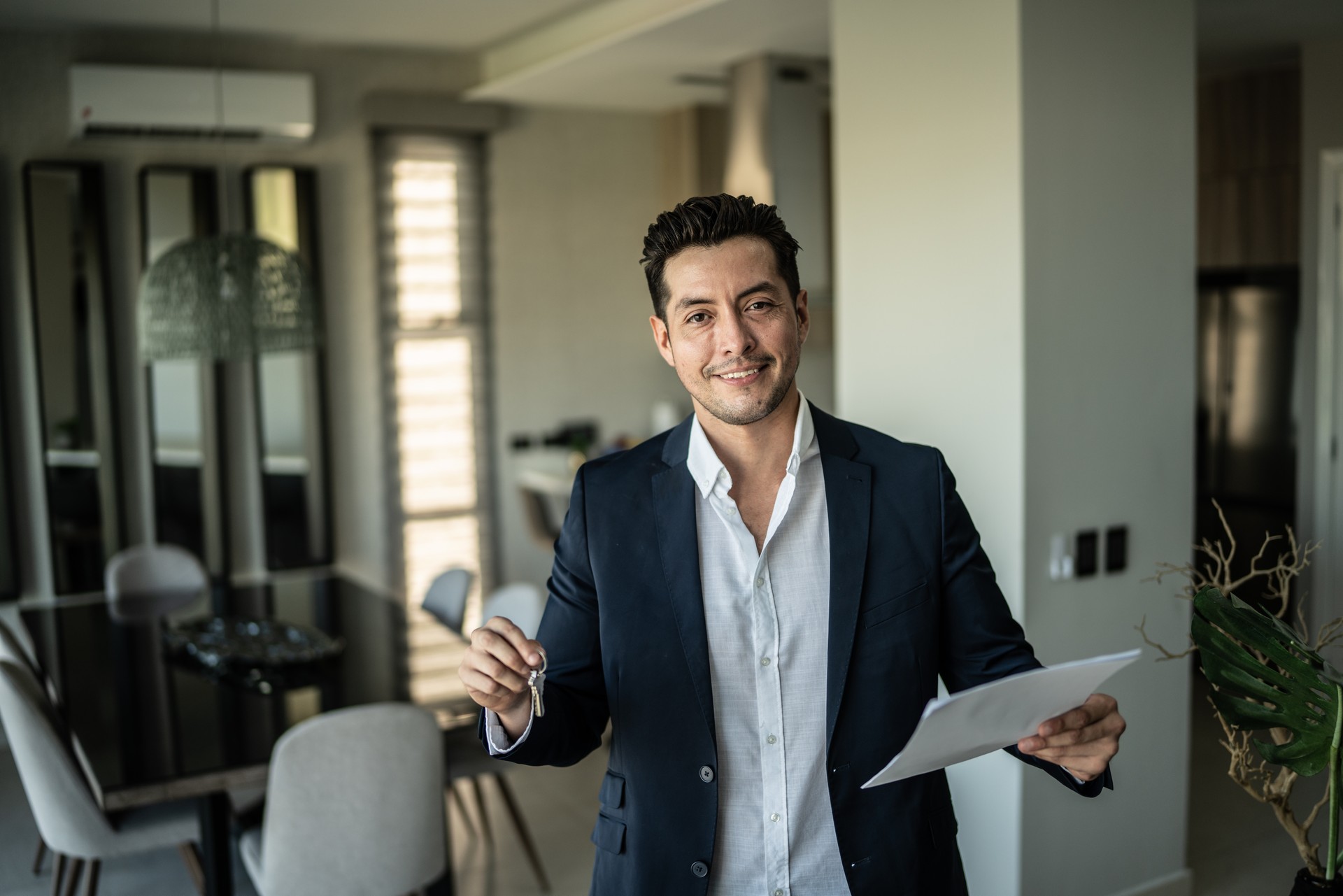 Portrait of a real estate agent holding document and house key at home